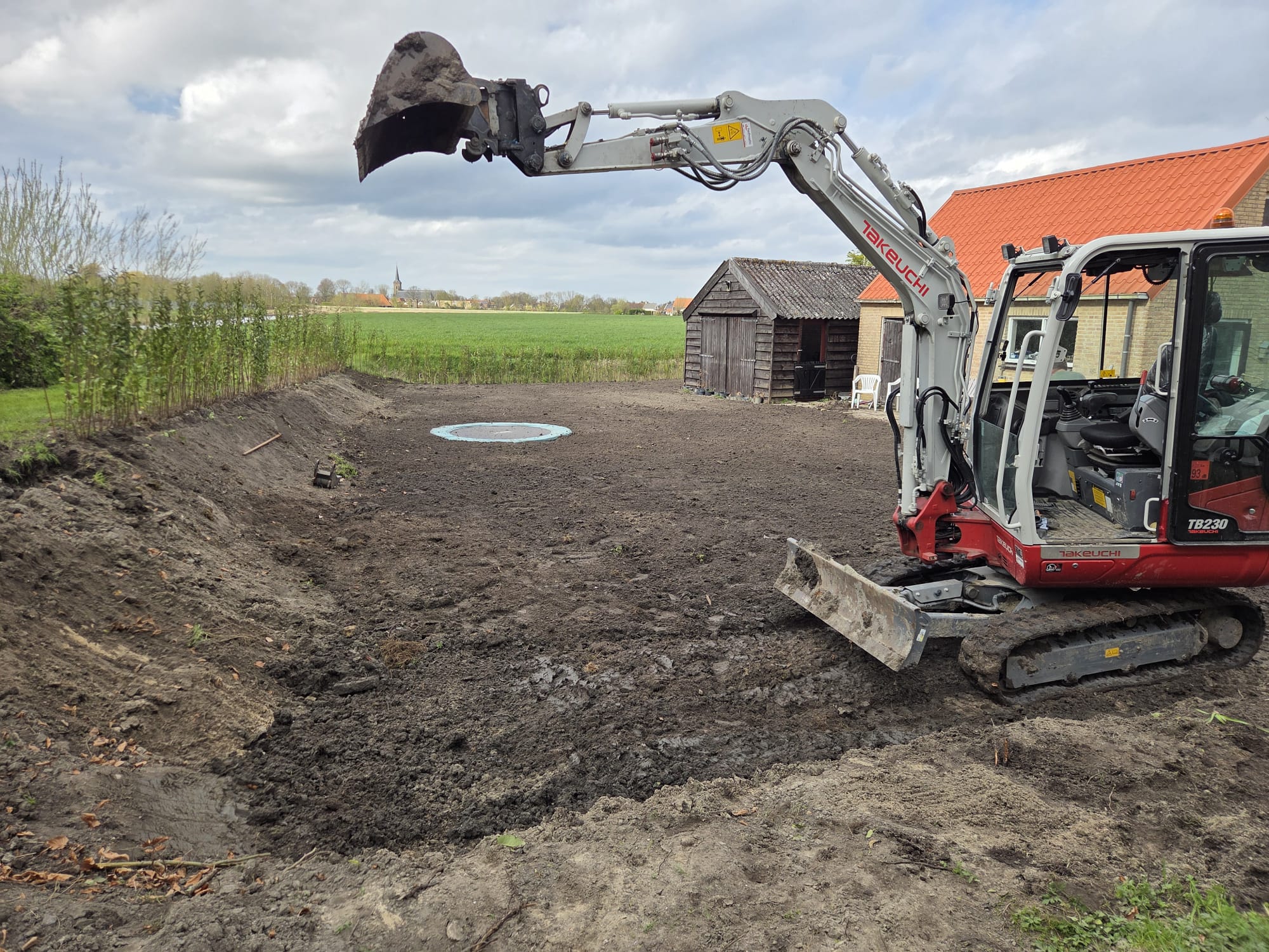 Graafmachine graaft een rechte uitsparing naast een schuur