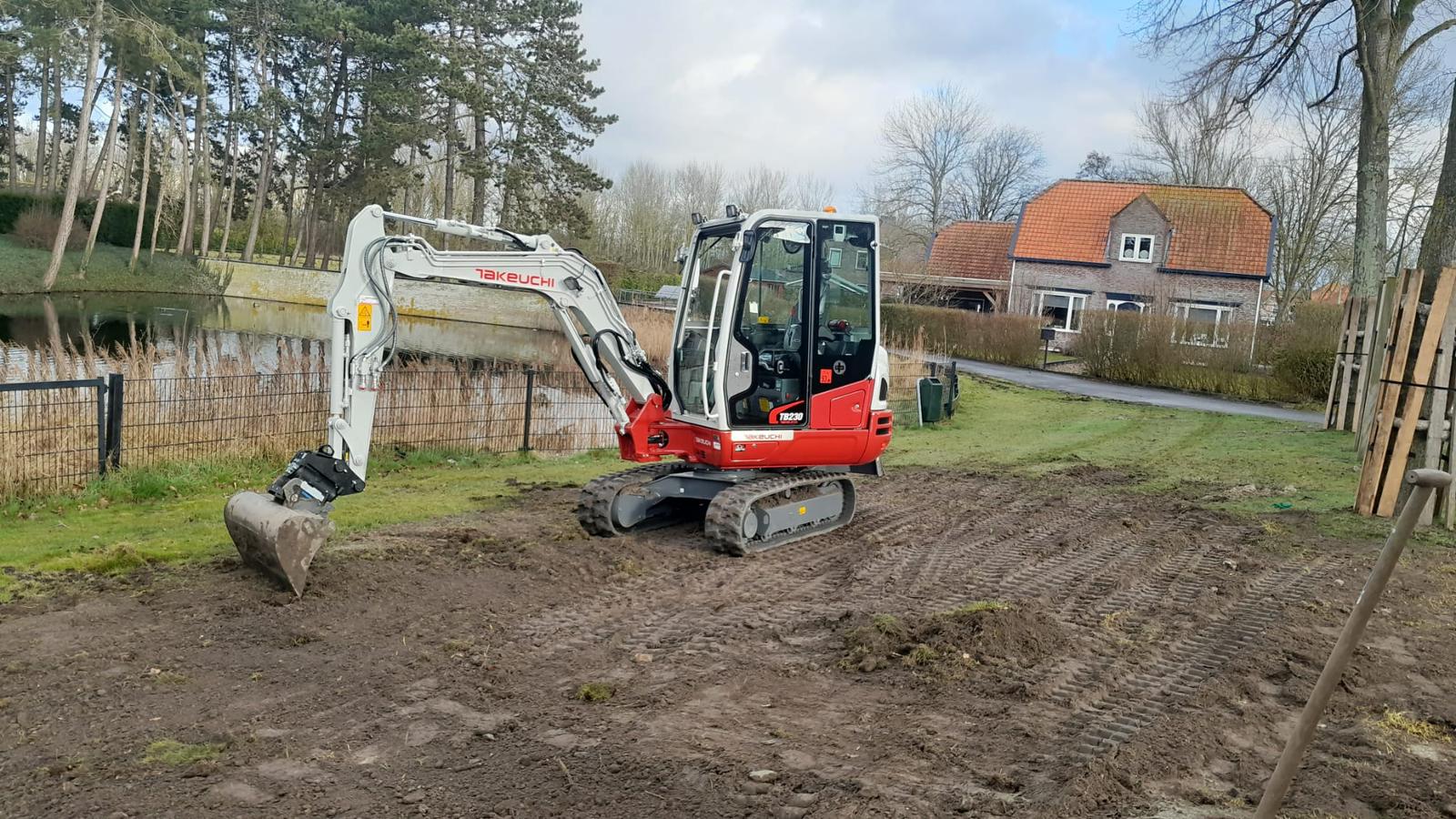 Graafmachine strijkt grond glad langs een sloot